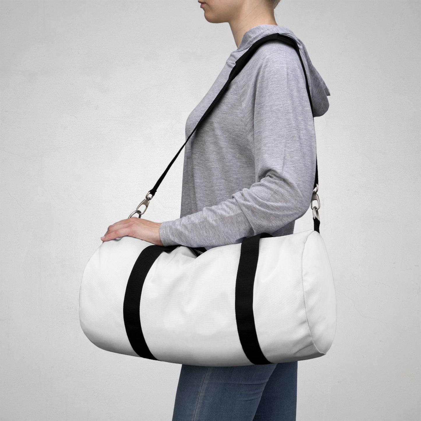 
                  
                    White duffel bag with black strap carried over shoulder
                  
                