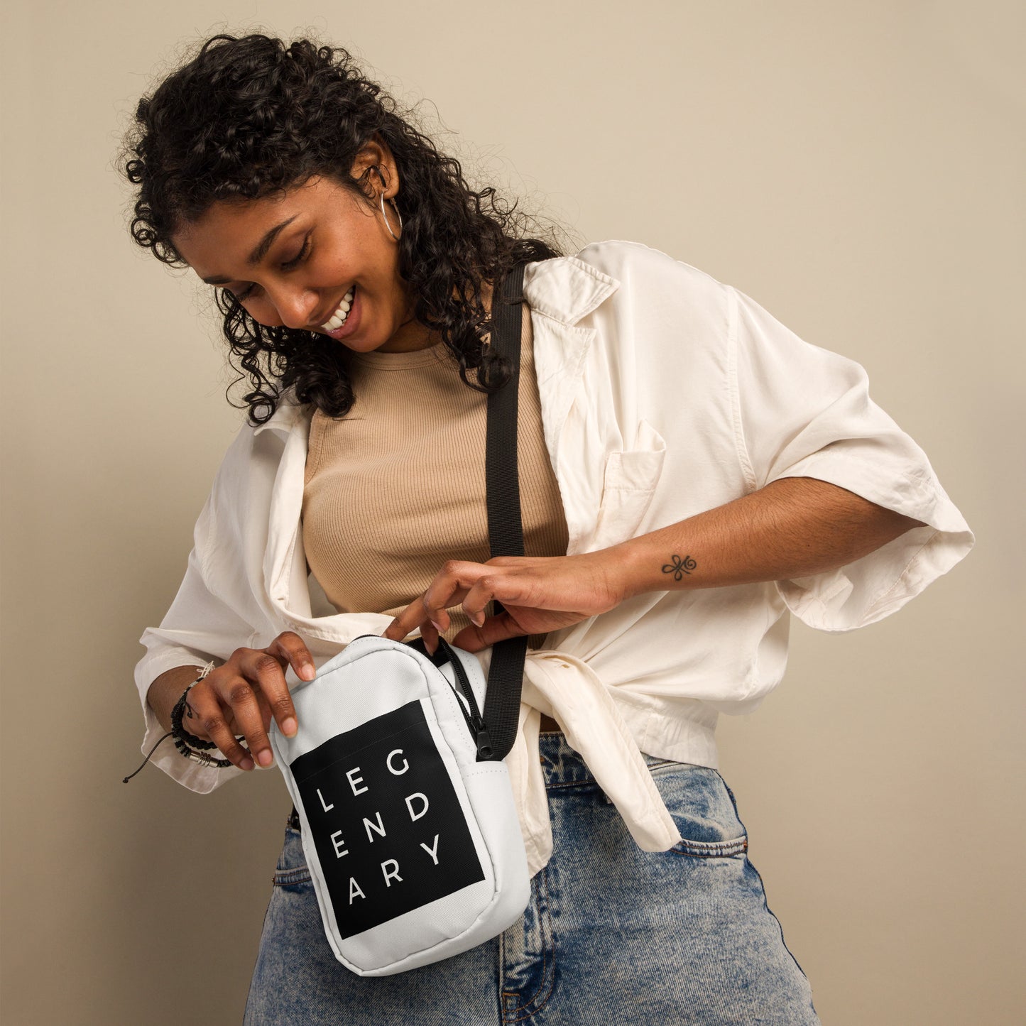 
                  
                    White utility crossbody bag with black strap and logo patch, worn across body
                  
                