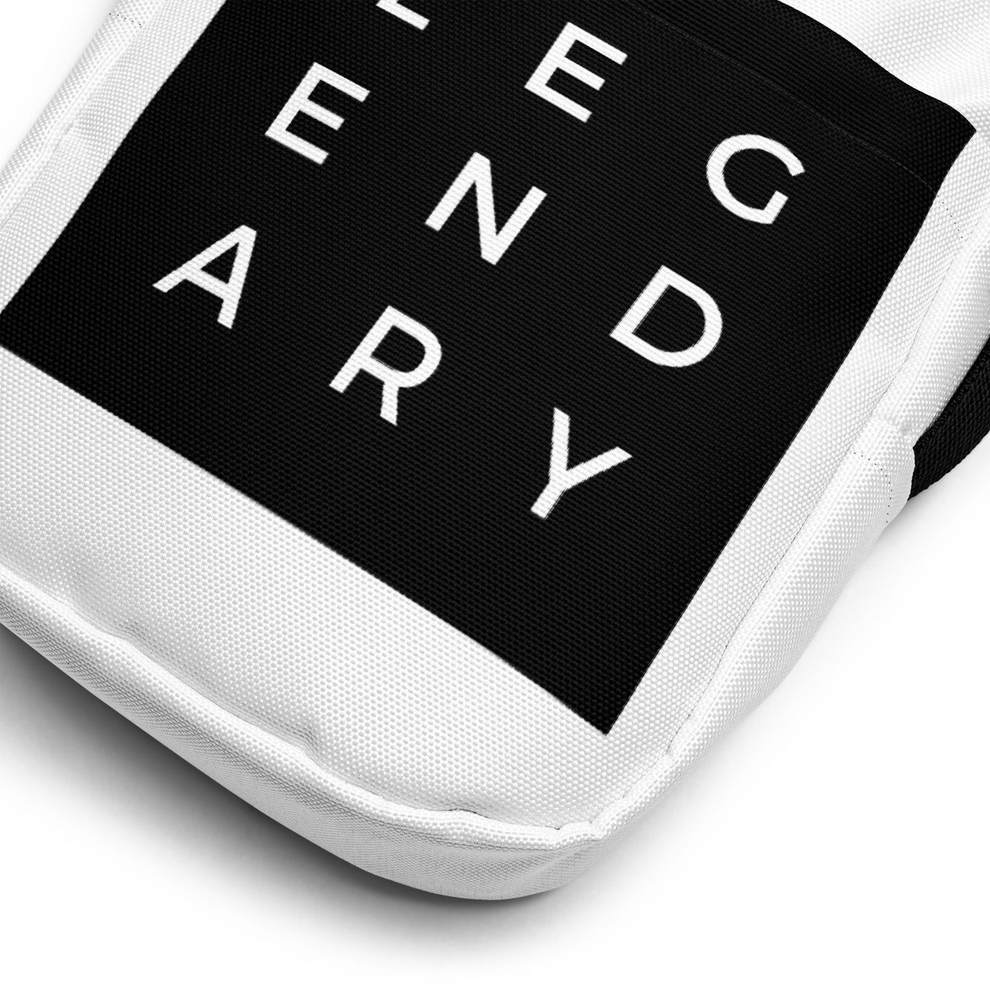 
                  
                    Close-up of white bag corner with black logo patch and stitched edge
                  
                