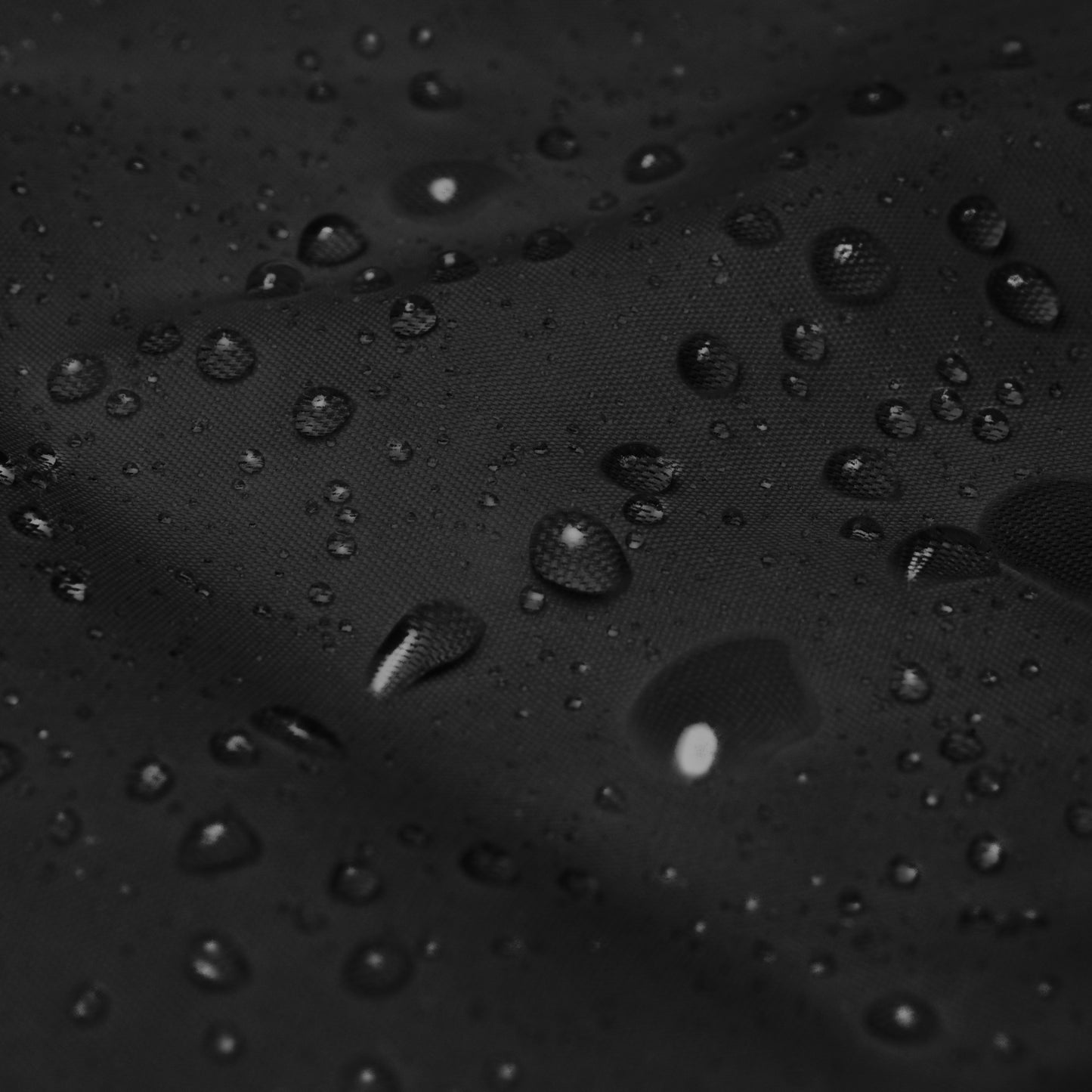 
                  
                    Black windbreaker fabric with water droplets, textured protective finish
                  
                
