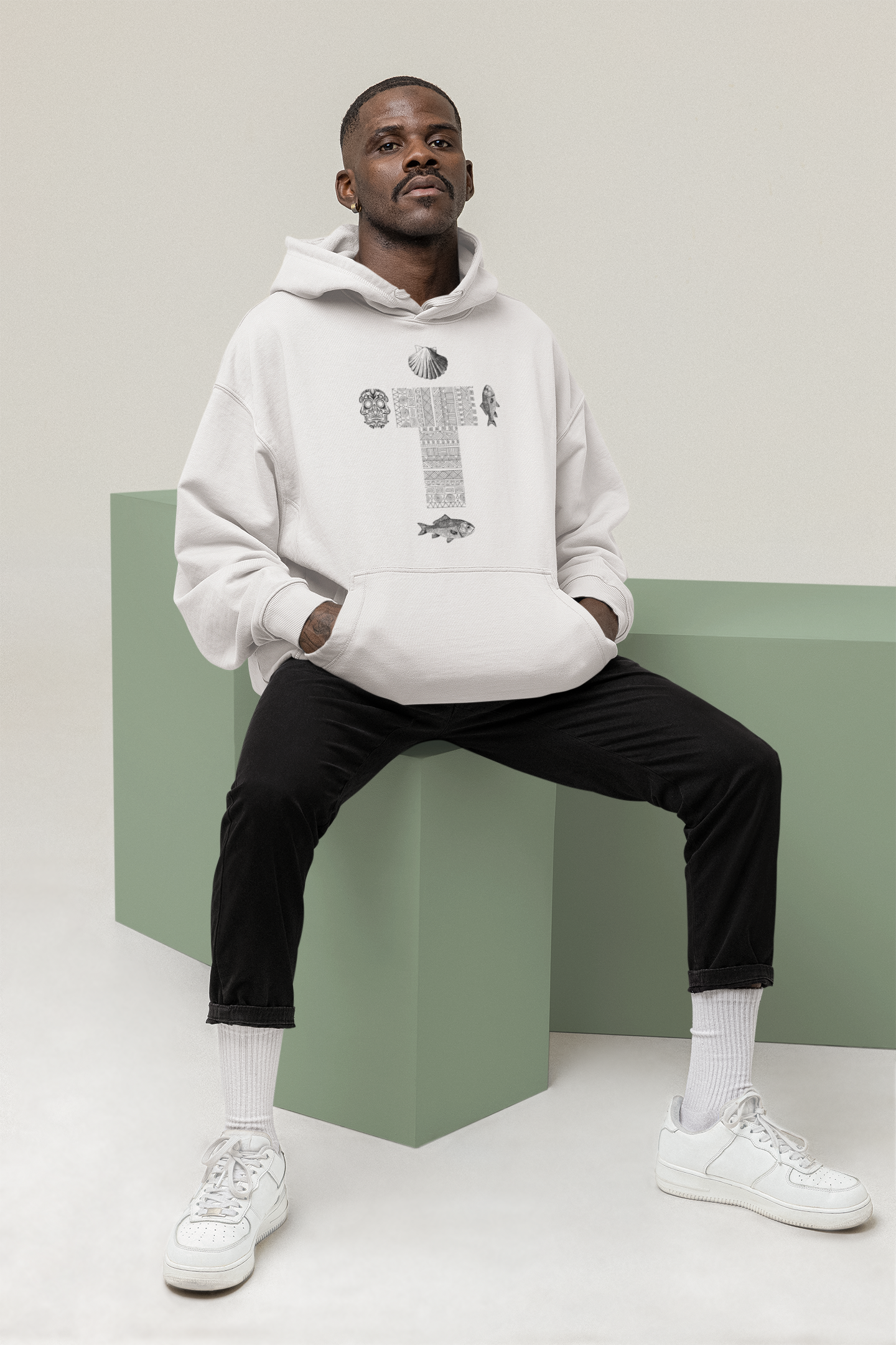 
                  
                    White unisex hoodie with cross, skull, fish, and shell front graphic, seated
                  
                
